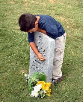 autistic-boy-embracing-grave-with-fresh-flowers