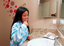 girl with autism brushing her teeth in the bathroom