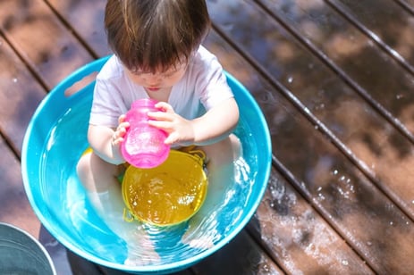 Young toddler boy with autism playing with water outside