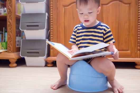 boy with autism potty training while reading book