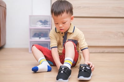 boy with autism putting on socks and shoes