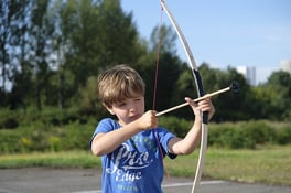 autistic boy using bow during archery at camp