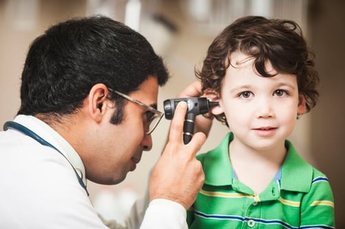doctor checking little boy with autism hearing
