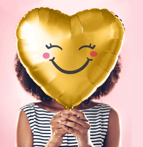 woman-covering-face-with-a-happy-face-foil-balloon
