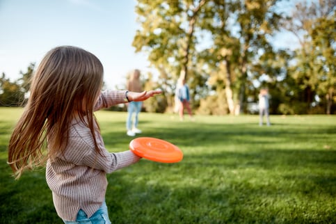 girl with autism playing with frisbee outside