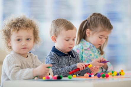 group of preschool students playing with sensory pom poms together in class