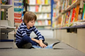autistic boy reading a book on the floor 