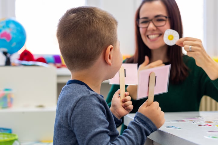 Preschooler with autism practicing correct pronunciation with a female speech therapist