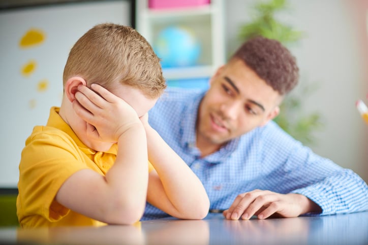 boy with autism upset being consoled by teacher