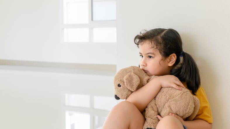 little girl with autism sitting with bear to calm down