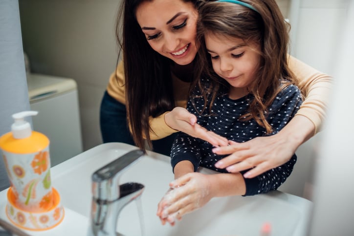mother helping girl with autism to wash her hands