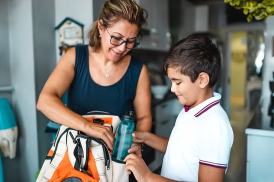 mother helping boy with autism pack his backpack